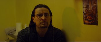 Movie still from “Starred Up” (2013), directed by David Mackenzie – A man sitting in front of a yellow wall smoking a cigarette; Close Up shot, Low angle
