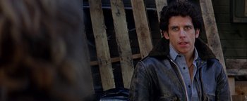 Movie still from “Starsky & Hutch” (2004), directed by Todd Phillips – A man in a leather jacket is sitting in front of a wooden fence; Close Up shot, Over the shoulder angle