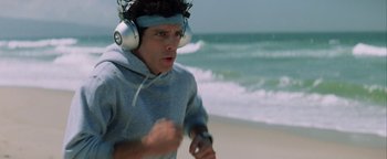 Movie still from “Starsky & Hutch” (2004), directed by Todd Phillips – A young man wearing headphones while running on the beach; Medium shot, High angle