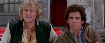 Movie still from “Starsky & Hutch” (2004), directed by Todd Phillips – Two men sitting next to each other in front of a red door; Close Up shot, High angle