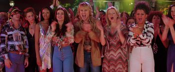 Movie still from “Starsky & Hutch” (2004), directed by Todd Phillips – A group of people standing next to each other in a room; Medium shot, Low angle