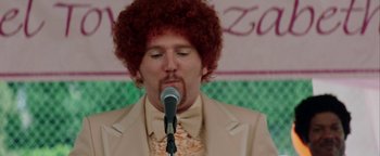 Movie still from “Starsky & Hutch” (2004), directed by Todd Phillips – A man with a red wig and a microphone; Close Up shot, Over the shoulder angle