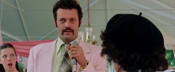 Movie still from “Starsky & Hutch” (2004), directed by Todd Phillips – A man in a pink suit is holding a microphone in his hand; Close Up shot, Low angle