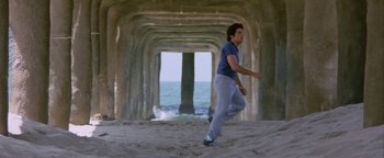 Movie still from “Starsky & Hutch” (2004), directed by Todd Phillips – A man is running on the beach under a pier; Wide shot, Low angle