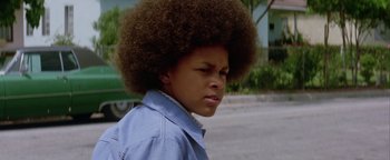 Movie still from “Starsky & Hutch” (2004), directed by Todd Phillips – A young man with a large afro is standing in the street; Close Up shot, Low angle