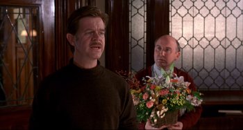 Movie still from “State and Main” (2000), directed by David Mamet – A man holding a basket of flowers next to another man in a brown sweater; Medium shot, Over the shoulder angle