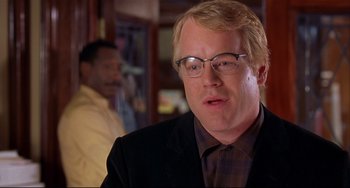 Movie still from “State and Main” (2000), directed by David Mamet – A person wearing a suit and glasses; Close Up shot, Over the shoulder angle