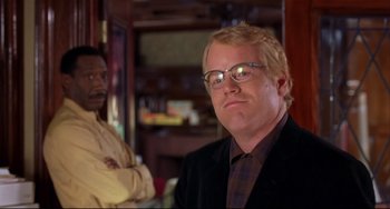 Movie still from “State and Main” (2000), directed by David Mamet – A man in a suit and glasses standing next to another man; Close Up shot, Over the shoulder angle