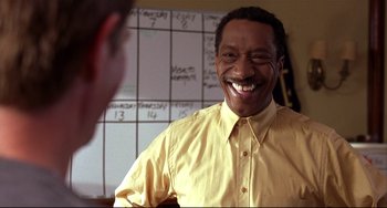 Movie still from “State and Main” (2000), directed by David Mamet – A man in a yellow shirt smiling at a man in a white shirt; Close Up shot, Over the shoulder angle