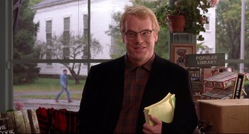 Movie still from “State and Main” (2000), directed by David Mamet – A man in a black jacket holding a yellow piece of paper; Medium shot, Over the shoulder angle
