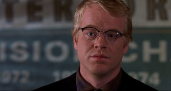 Movie still from “State and Main” (2000), directed by David Mamet – A person wearing glasses and a suit; Close Up shot, Over the shoulder angle