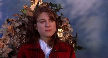 Movie still from “State and Main” (2000), directed by David Mamet – A woman wearing a red jacket standing in front of a bunch of grapes; Close Up shot, Low angle