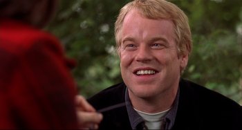 Movie still from “State and Main” (2000), directed by David Mamet – A man that is sitting down and smiling; Close Up shot, Over the shoulder angle