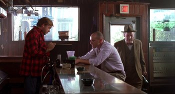 Movie still from “State and Main” (2000), directed by David Mamet – A man sitting at a bar talking to another man in front of him; Medium shot, Over the shoulder angle