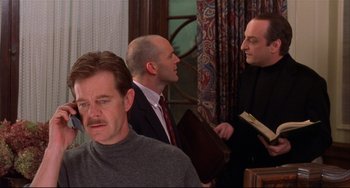 Movie still from “State and Main” (2000), directed by David Mamet – A group of men standing next to each other in a room; Medium shot, Over the shoulder angle