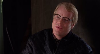 Movie still from “State and Main” (2000), directed by David Mamet – A person wearing glasses and a jacket; Close Up shot, Over the shoulder angle