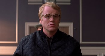 Movie still from “State and Main” (2000), directed by David Mamet – A man with blonde hair wearing glasses and a black jacket; Close Up shot, Over the shoulder angle