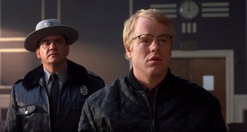 Movie still from “State and Main” (2000), directed by David Mamet – A man with blonde hair wearing glasses and a black jacket; Close Up shot, Over the shoulder angle