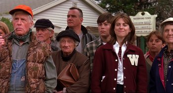 Movie still from “State and Main” (2000), directed by David Mamet – A group of people standing next to each other in front of a house; Medium shot, Low angle