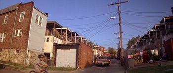 Movie still from “Step Up” (2006), directed by Anne Fletcher – A car parked on the side of the road in front of a building; Extreme Wide shot, Low angle