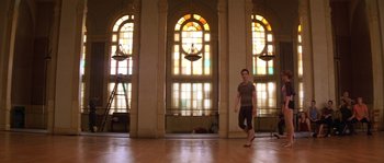 Movie still from “Step Up” (2006), directed by Anne Fletcher – A man standing in front of stained glass windows in a room; Wide shot, Low angle