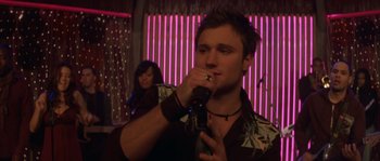 Movie still from “Step Up” (2006), directed by Anne Fletcher – A man holding a microphone and a woman standing behind him; Close Up shot, Low angle