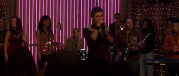 Movie still from “Step Up” (2006), directed by Anne Fletcher – A man singing into a microphone in front of a group of people; Medium shot, Over the shoulder angle