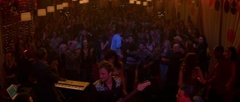 Movie still from “Step Up” (2006), directed by Anne Fletcher – A group of people in a room with a guitar and a piano; Extreme Wide shot, High angle