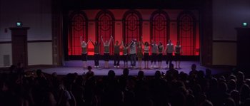 Movie still from “Step Up” (2006), directed by Anne Fletcher – A group of people standing on a stage holding their hands up in the air; Extreme Wide shot, Low angle