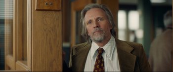 Movie still from “Stockholm” (2018), directed by Robert Budreau – A man with long gray hair wearing a suit and tie; Close Up shot, Over the shoulder angle