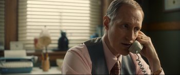 Movie still from “Stockholm” (2018), directed by Robert Budreau – A person wearing a suit and tie; Close Up shot, Over the shoulder angle