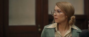 Movie still from “Stockholm” (2018), directed by Robert Budreau – A woman wearing glasses and a green jacket looking to her left; Close Up shot, Over the shoulder angle
