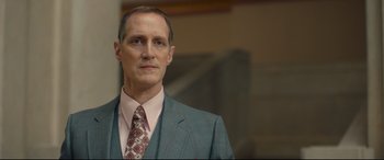 Movie still from “Stockholm” (2018), directed by Robert Budreau – A person wearing a suit and tie; Close Up shot, Low angle