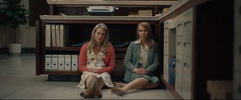 Movie still from “Stockholm” (2018), directed by Robert Budreau – Two women sitting next to each other on the ground; Wide shot, Low angle