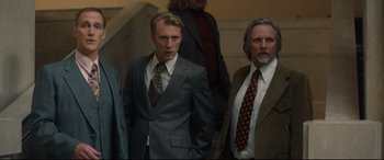 Movie still from “Stockholm” (2018), directed by Robert Budreau – A group of men standing next to each other wearing suits; Medium shot, Low angle