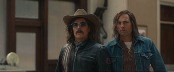 Movie still from “Stockholm” (2018), directed by Robert Budreau – A man in a cowboy hat standing next to another man; Medium shot, Low angle