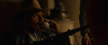 Movie still from “Stockholm” (2018), directed by Robert Budreau – A man in a cowboy hat talking on a phone; Close Up shot, Low angle