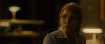 Movie still from “Stockholm” (2018), directed by Robert Budreau – A woman wearing glasses looking at the camera; Close Up shot, Over the shoulder angle