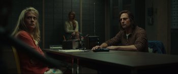 Movie still from “Stockholm” (2018), directed by Robert Budreau – A man sitting at a table in front of a woman; Medium shot, Low angle