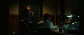 Movie still from “Stockholm” (2018), directed by Robert Budreau – A man standing in front of a woman in a dark room; Medium shot, Over the shoulder angle