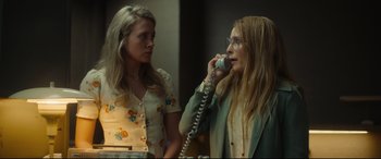 Movie still from “Stockholm” (2018), directed by Robert Budreau – Two women standing next to each other talking on a phone; Medium shot, Low angle