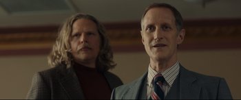 Movie still from “Stockholm” (2018), directed by Robert Budreau – Two men standing next to each other in front of a wall; Close Up shot, Low angle