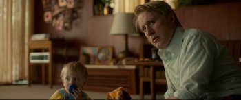 Movie still from “Stockholm” (2018), directed by Robert Budreau – A man and a baby in a living room; Medium shot, Over the shoulder angle