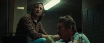 Movie still from “Stockholm” (2018), directed by Robert Budreau – A man sitting next to another man in a room; Medium shot, Over the shoulder angle
