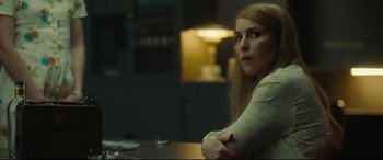 Movie still from “Stockholm” (2018), directed by Robert Budreau – A woman sitting at a table in a dark room; Close Up shot, Over the shoulder angle