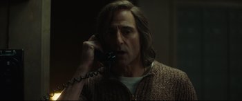 Movie still from “Stockholm” (2018), directed by Robert Budreau – A man talking on a phone in a dark room; Close Up shot, Low angle