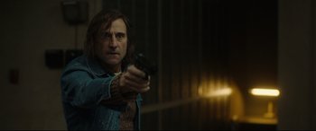 Movie still from “Stockholm” (2018), directed by Robert Budreau – A man holding a gun in a room with lights; Medium shot, Low angle