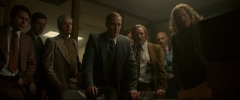 Movie still from “Stockholm” (2018), directed by Robert Budreau – A group of men standing in front of a mirror; Medium shot, Low angle