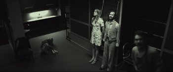 Movie still from “Stockholm” (2018), directed by Robert Budreau – A man and a woman standing next to each other in a room; Wide shot, High angle