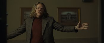 Movie still from “Stockholm” (2018), directed by Robert Budreau – A man with long blonde hair wearing a jacket; Medium shot, Low angle